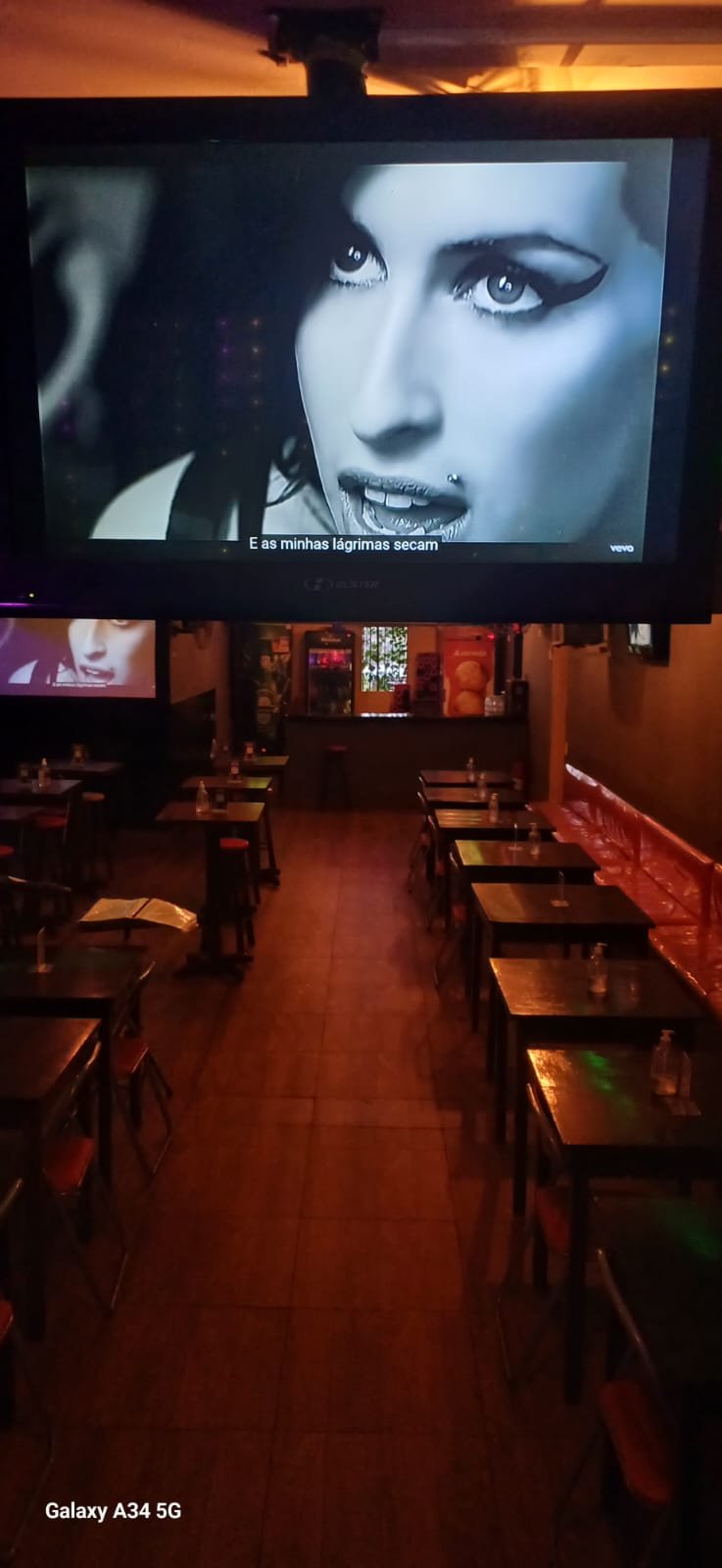 Telão exibindo vídeo de karaokê no Guinga's Bar